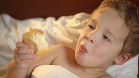 一个可爱的小男孩在床上吃面包视频