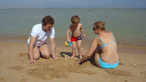 在海滩上陪孩子玩耍的一家三口21秒视频