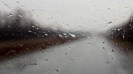 下雨天在公路上行驶的汽车前玻璃窗上的雨刮器在不停地摆动视频