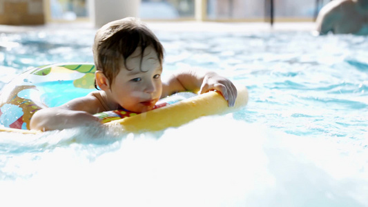 带着橡胶圈的小男孩在游泳池中游泳视频