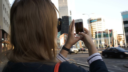 女人用手机拍摄城市建筑[品牌手机]视频