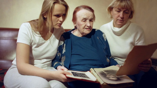 女儿母亲和祖母看着旧的家庭相册奶奶回答孙女的问题视频