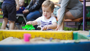 小男孩在院子里的沙坑里玩塑料鳄鱼和汽车6秒视频