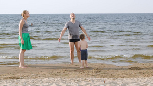 年轻的父母和小儿子在海边的海滩上打球游戏10秒视频