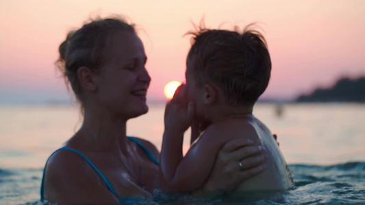 在日落海滨游泳的母亲与儿子视频