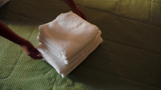 女人把一堆干净的白色毛巾整齐地放在床视频
