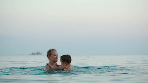 年轻的母亲抱着儿子在海水里玩跳高游戏21秒视频