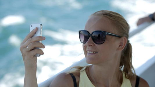 女人戴着太阳镜在船上用手机自拍[戴起]视频