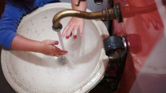 一个小孩子在老式水槽里洗手然后关掉水龙头的高角度和特写镜头视频