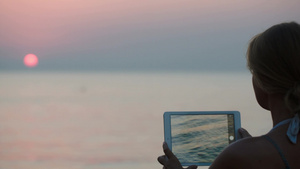 年轻的女人用平板电脑拍日落的照片20秒视频