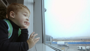 母亲带着小男孩看着窗外的机场24秒视频