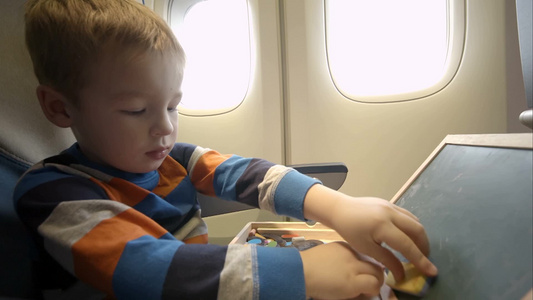飞机上的小男孩用白板擦在儿童绘画板上来回擦除视频