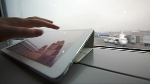 一位女性在机场的窗户旁使用平板电脑上打字的特写镜头23秒视频