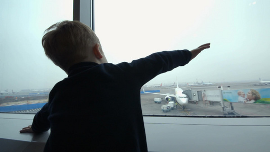 机场的小男孩从窗户看着飞机用手模仿视频