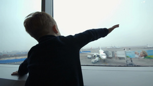 机场的小男孩从窗户看着飞机用手模仿17秒视频