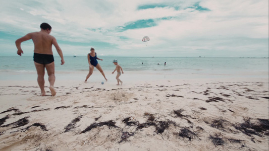 父母陪儿子在海滩上踢球视频