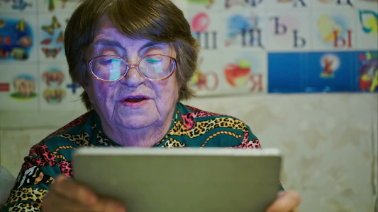 老年妇女在看平板电脑上滚动照片视频