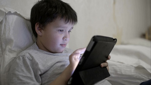 少年男孩在床上靠在枕头上使用笔记本电脑学习13秒视频