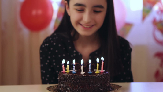 快乐的年轻女孩在生日蛋糕上吹蜡烛视频