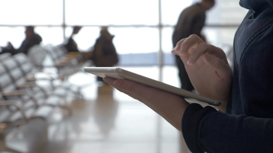 女乘客在机场候车室里用iPad工作视频