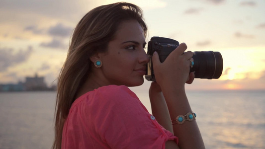 年轻漂亮金发女孩拿着相机在拍摄加勒比海的风景视频