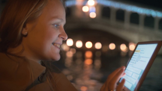 女人在夜间威尼斯乘船旅行时使用平板电脑聊天视频