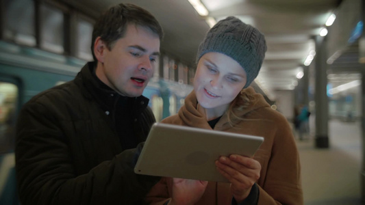 在地铁站年轻人和女人用平板电脑讨论一些问题视频
