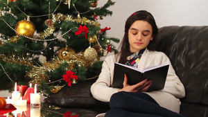 女孩在家坐在圣诞树旁看书29秒视频