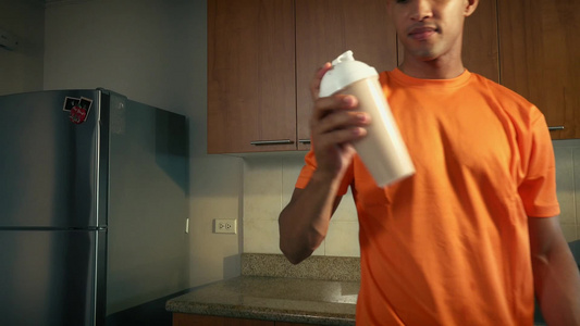 年轻的男子在厨房喝奶昔视频