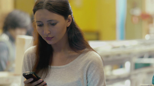 微笑的黑发女人在咖啡馆里用智能手机发信息视频