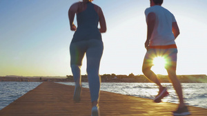 太阳刚刚升起的码头上一对年轻夫妇在跑步锻炼32秒视频