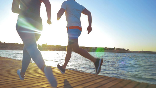阳光的早晨两个运动员在海岸上慢跑[运动量]视频