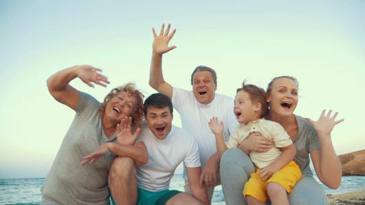 一个大家庭的成员坐在海滩上挥手视频
