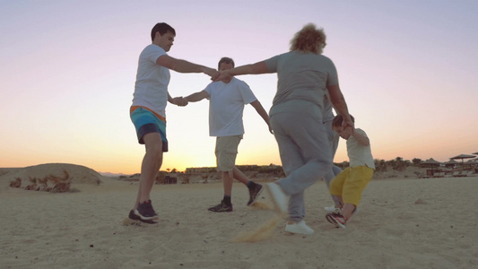 一个大家庭牵手围成圈在海滩上跳舞视频