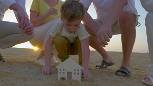 家人帮助男孩在海滩上堆砌房子25秒视频