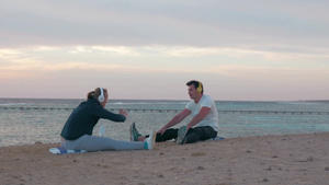 一对年轻夫妇坐在海滩听音乐做伸展运动51秒视频