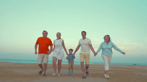 一个大家庭的父母和儿子还有祖父母一起牵手在海滩上跑步10秒视频