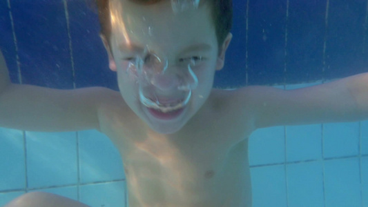 一个孩子在游泳池里睁大眼睛潜水视频