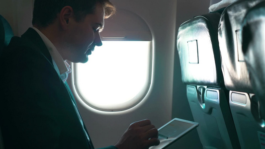 商务人士在飞机上用平板电脑工作视频