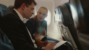 一家三口乘飞机旅行孩子在玩智能手机而父亲在和妻子交谈6秒视频