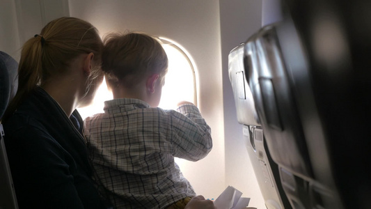 飞机上的母子俩看向窗外[隔窗]视频