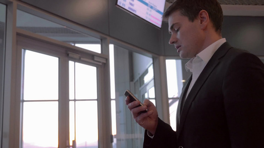 商务人士在机场使用手机和客户聊天[家庭用户]视频