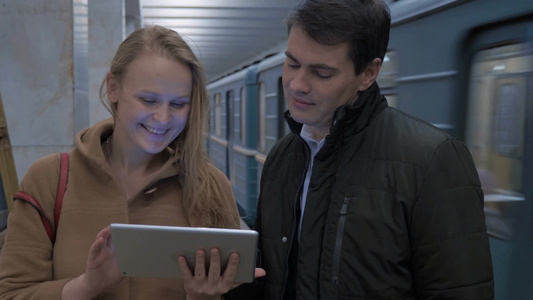 男女在地铁站里欢乐的在看ipad聊天视频