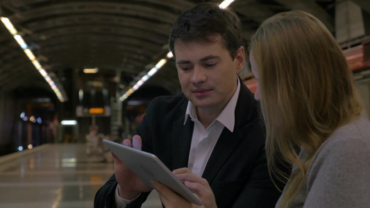 年轻人在地铁站用平板电脑讨论一些商业问题视频