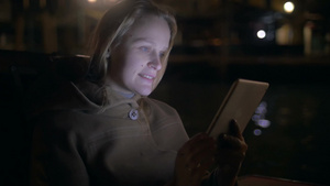 夜晚年轻的女人坐在船上玩手机18秒视频