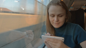 火车上的女性旅行者使用钢笔在手机上键入短信有时她看着窗外的风景44秒视频