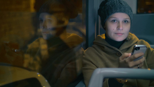 年轻的女人在公共汽车里使用手机视频
