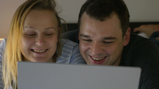 年轻夫妇晚上在床上用笔记本电脑看视频视频