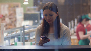 年轻的女人坐在咖啡馆里用智能手机给朋友写信息12秒视频