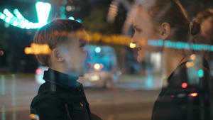 透过玻璃窗拍摄夜晚年轻母子在繁忙的街道上小男孩兴奋地和妈妈说话21秒视频